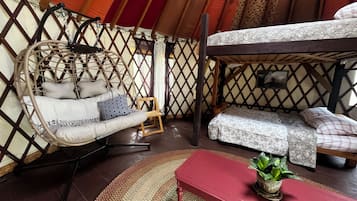 Un interior acogedor con una silla colgante, un banco y una cama.