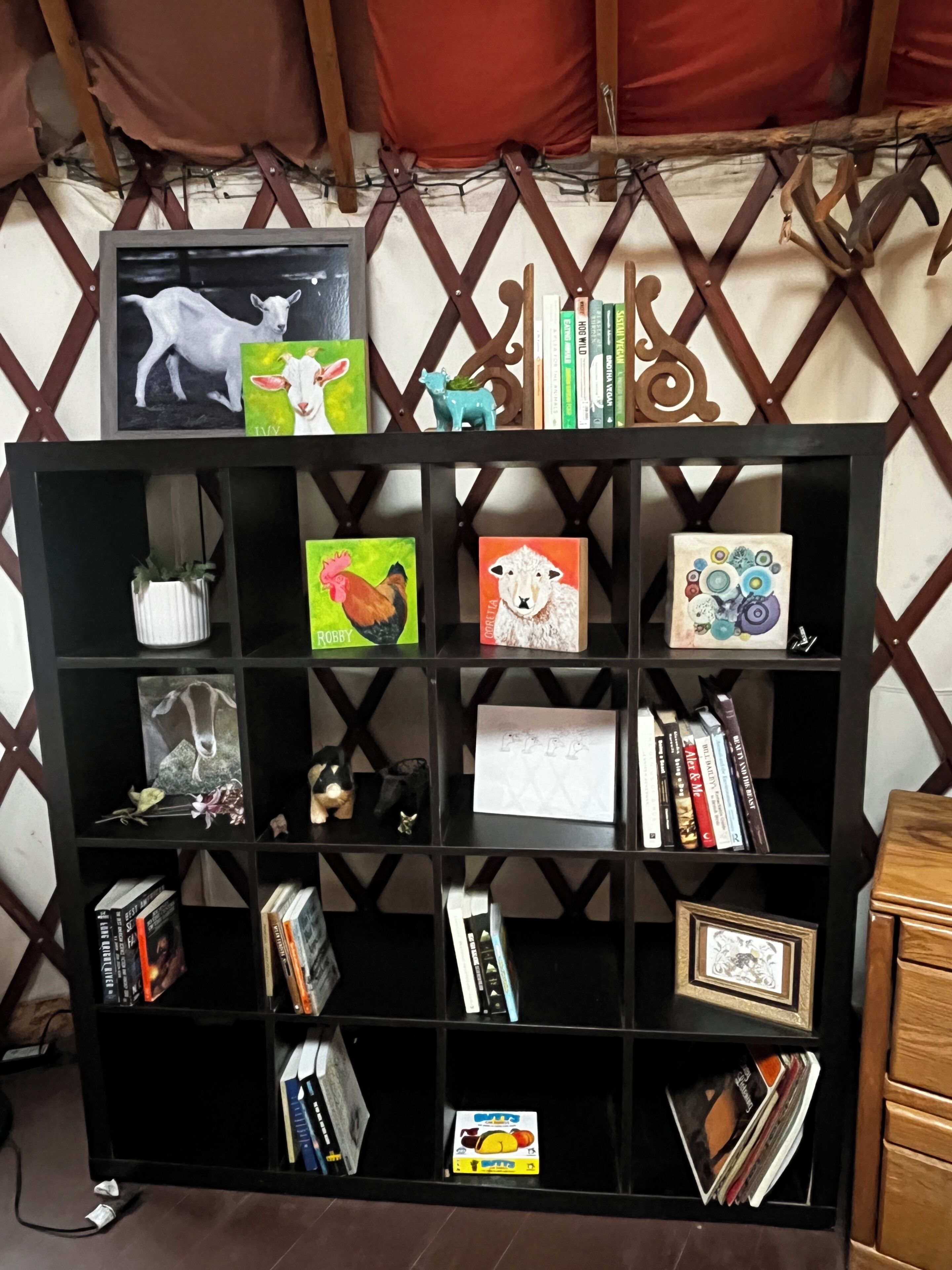 A black bookshelf with various items including framed artwork, books, and decorative objects.