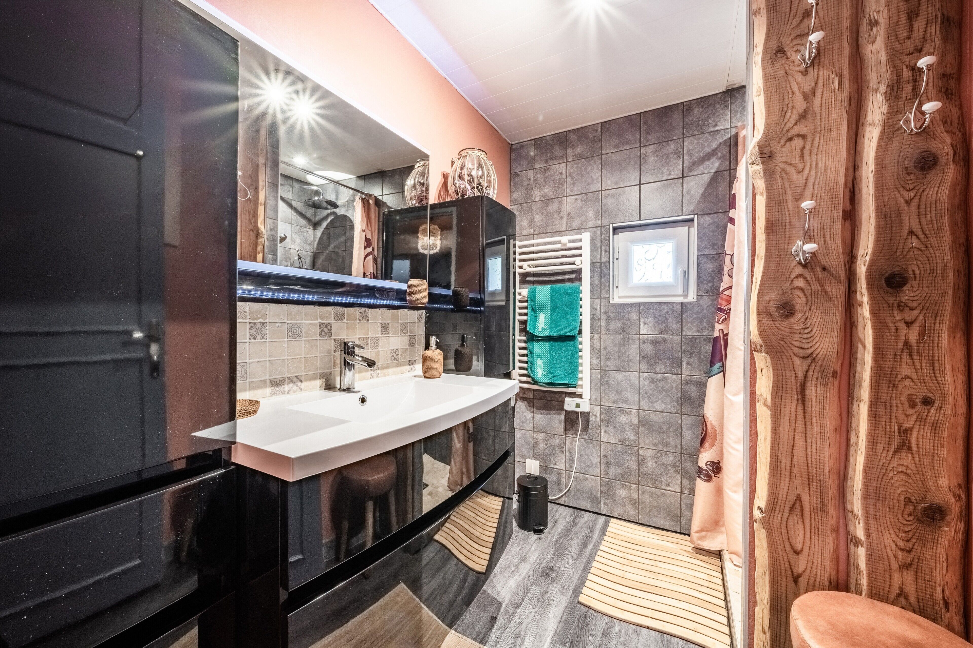 Een moderne badkamer met een grote spiegel, een wastafel en een douchehoek.