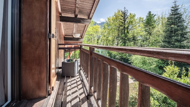 A wooden balcony with a view of a forest and mountains.