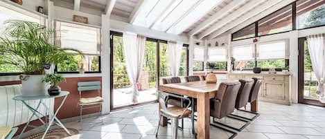 Un patio amplio con una mesa y sillas de madera, una planta en maceta y vistas al verdor exterior.