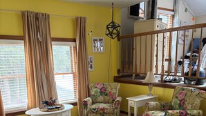 Una sala de estar con muebles de estampado floral, una alfombra con diseño y una escalera.