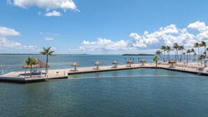Un port de plaisance doté d’un quai, de chaises longues et de parasols en chaume.