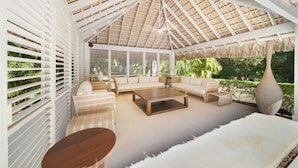 A covered outdoor seating area with a thatched roof, white lattice walls, and a sofa set. - Charming Italian Villa in Casa de Campo (Casa de Campo)