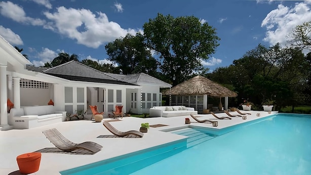 A modern outdoor pool area with lounge chairs, a thatched-roof structure, and a white building with multiple seating areas. - Charming Italian Villa in Casa de Campo (Casa de Campo)