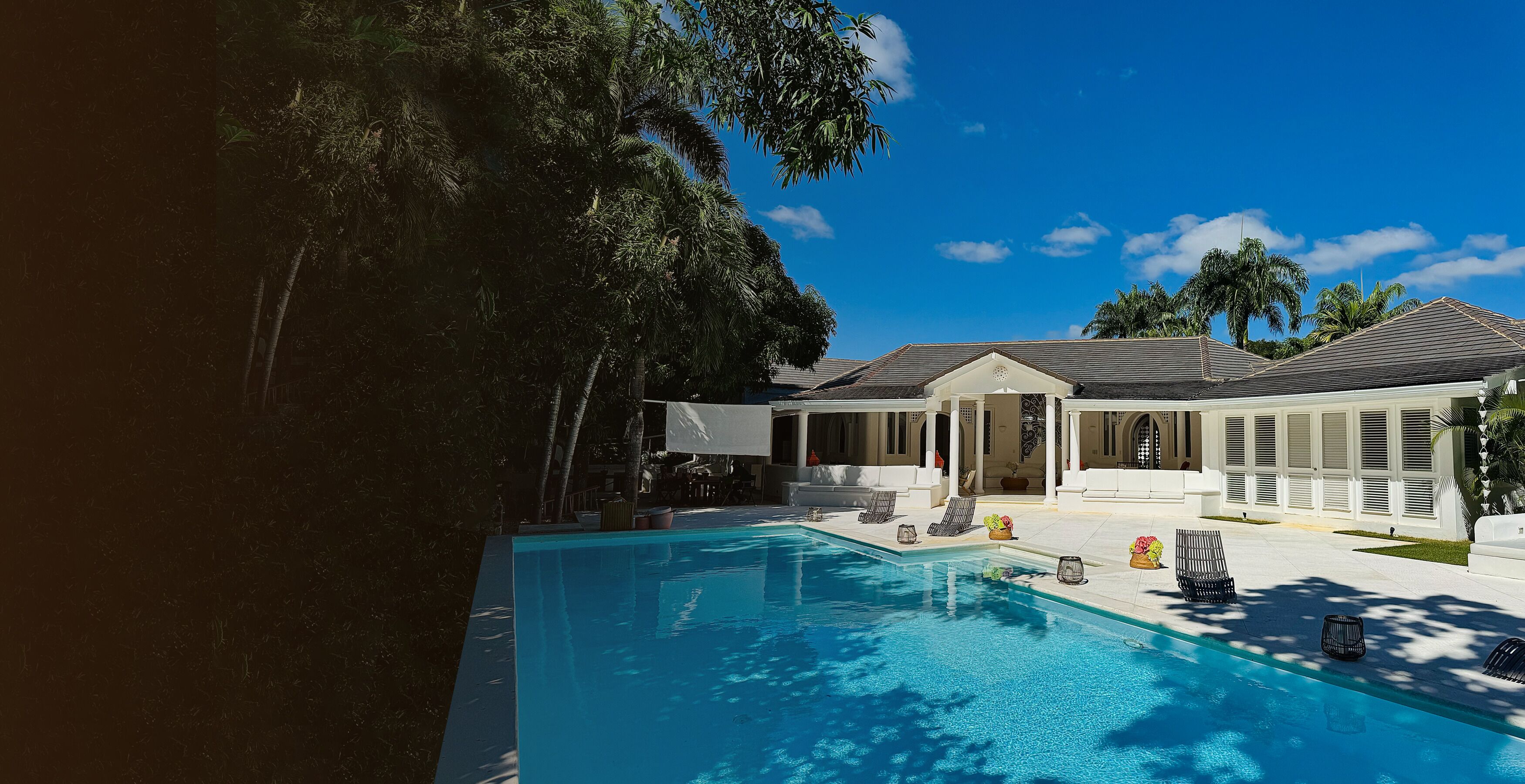 Piscina com espreguiçadeiras e área de estar coberta.