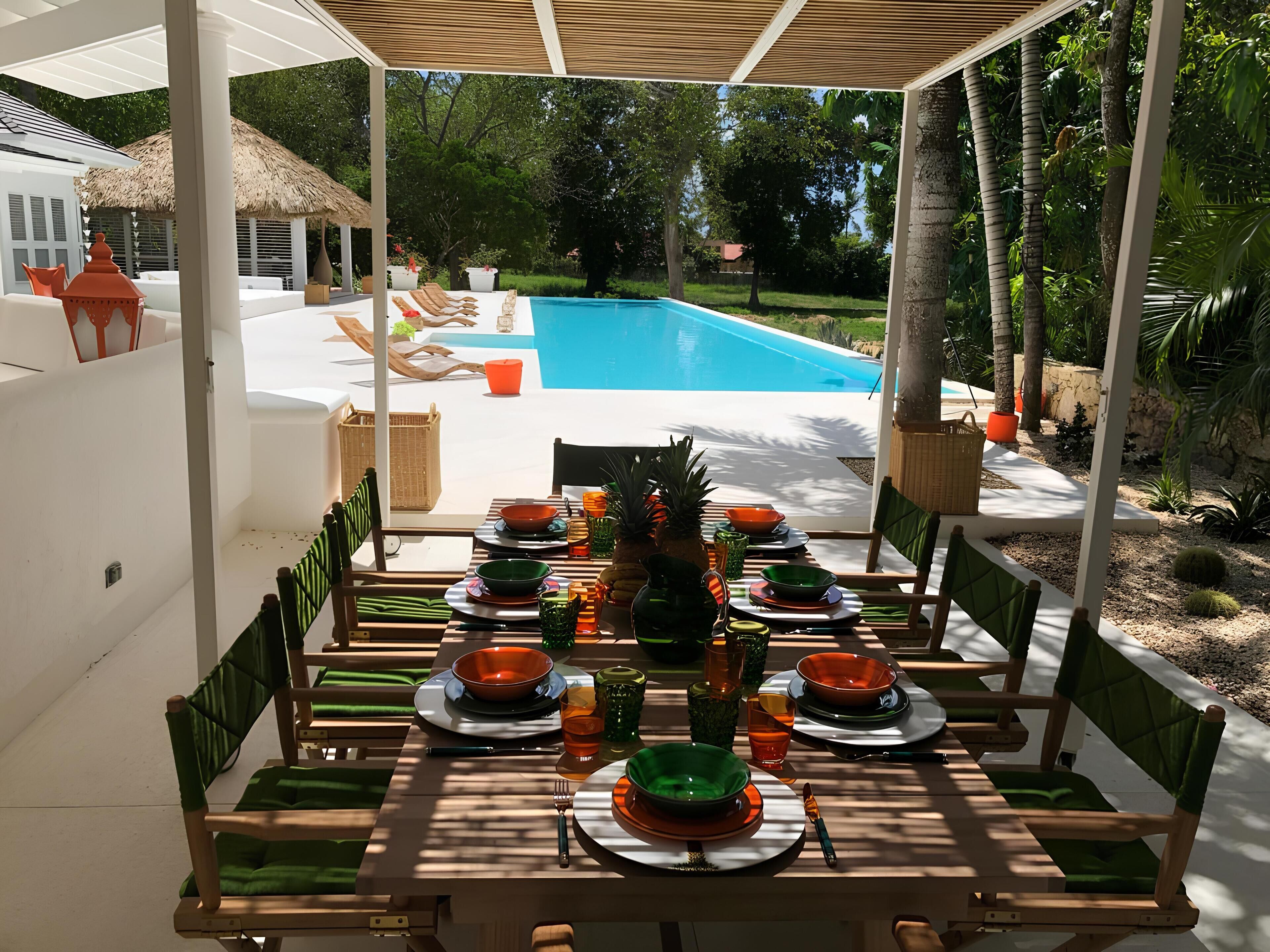 Comedor con vista a la piscina, mobiliario exterior y decoración tropical.