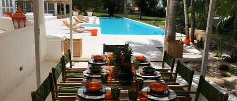Comedor con vista a la piscina, mobiliario exterior y decoración tropical.