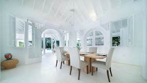 A spacious dining area with a large wooden table and four chairs, surrounded by white walls and large windows. - Charming Italian Villa in Casa de Campo (Casa de Campo)