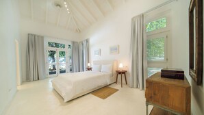 A spacious bedroom with a large bed, a wooden nightstand, a bedside table with a lamp, and a dresser. - Charming Italian Villa in Casa de Campo (Casa de Campo)