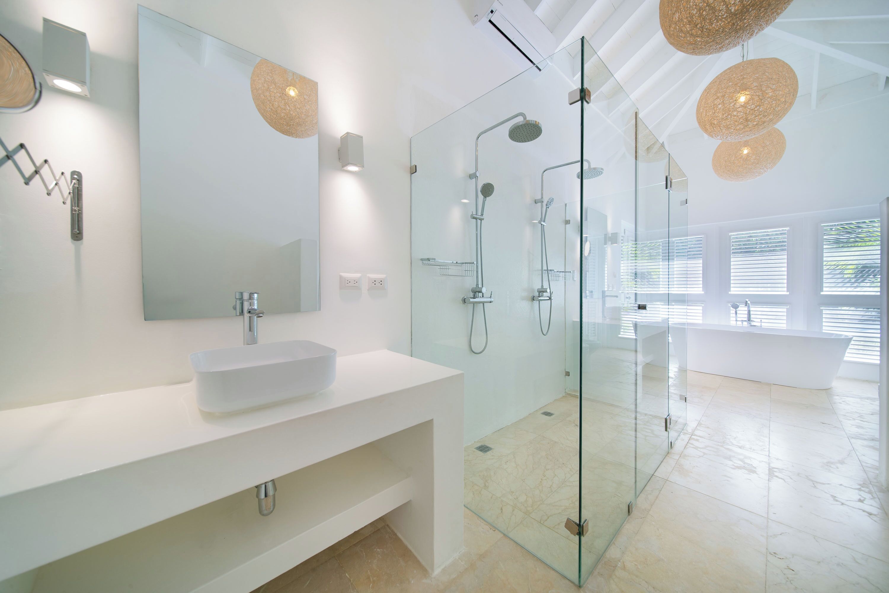Een moderne badkamer met een douchecabine van glas, een witte wastafel en een grote spiegel.