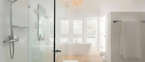 A modern bathroom with a glass-enclosed shower, a freestanding bathtub, and a toilet.