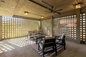 Ein überdachter Patio-Bereich mit Deckenventilator, einer Couch, einem Tisch und Stühlen.