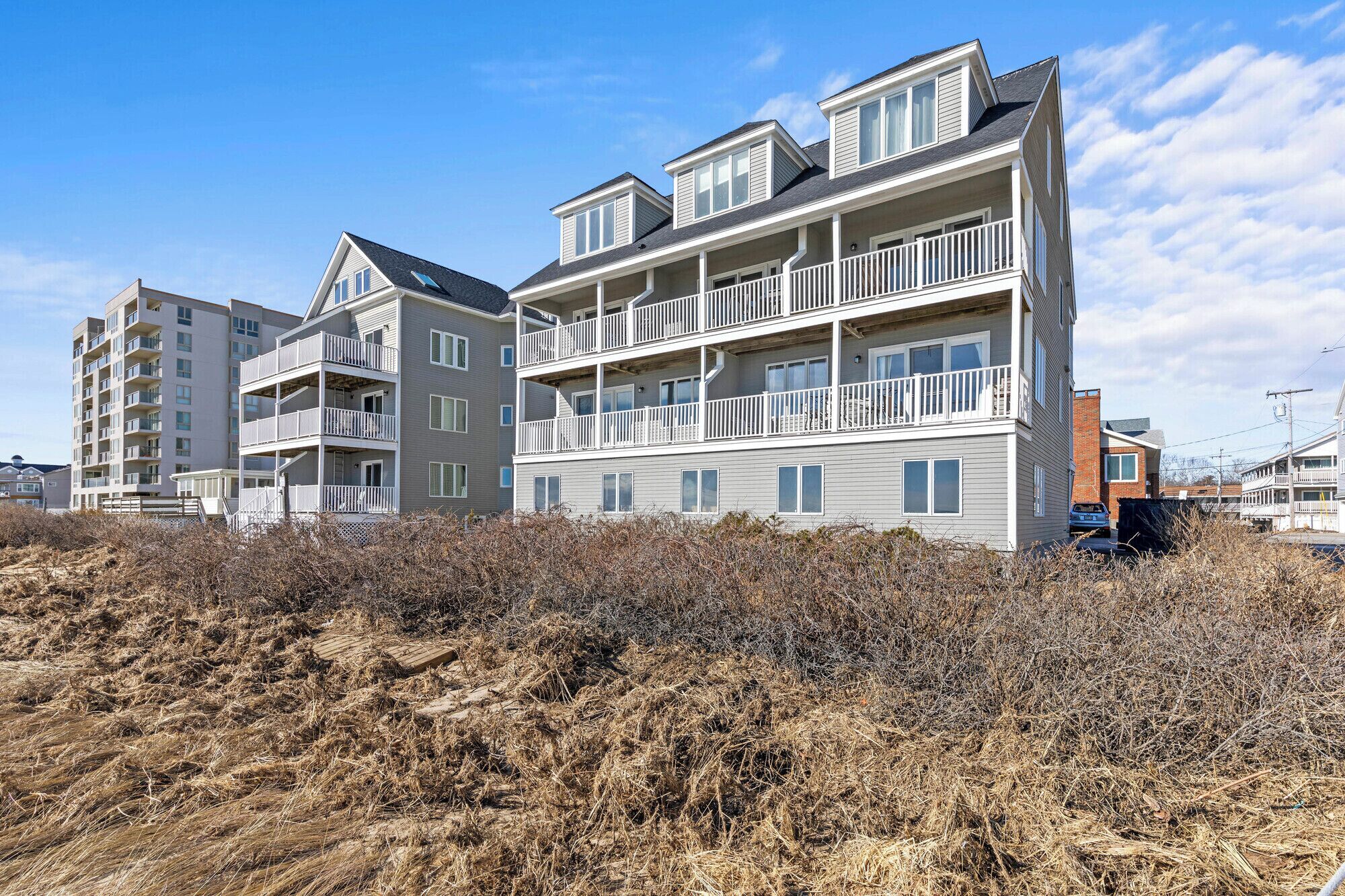 A multi-story residential building with balconies, a flat roof, and a brick section on the right side.