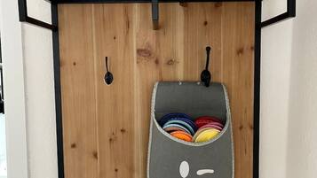 A wooden wall with a gray bag hanging from a black metal bracket, containing colorful items.