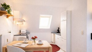 Een kleine keuken met een eethoek, een klein raam en een rood vloerkleed.