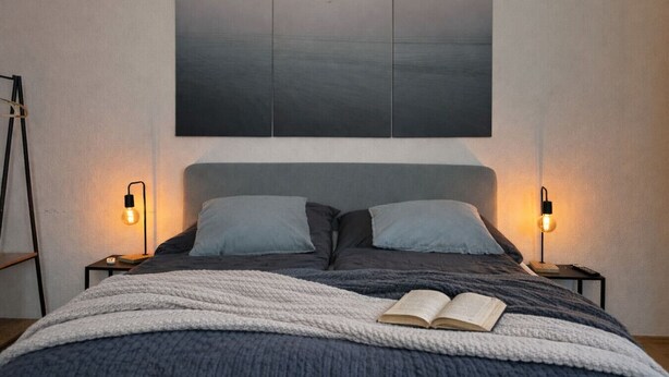 Une chambre à coucher moderne avec un grand lit, deux lampes de chevet et un grand tableau abstrait au-dessus du lit.
