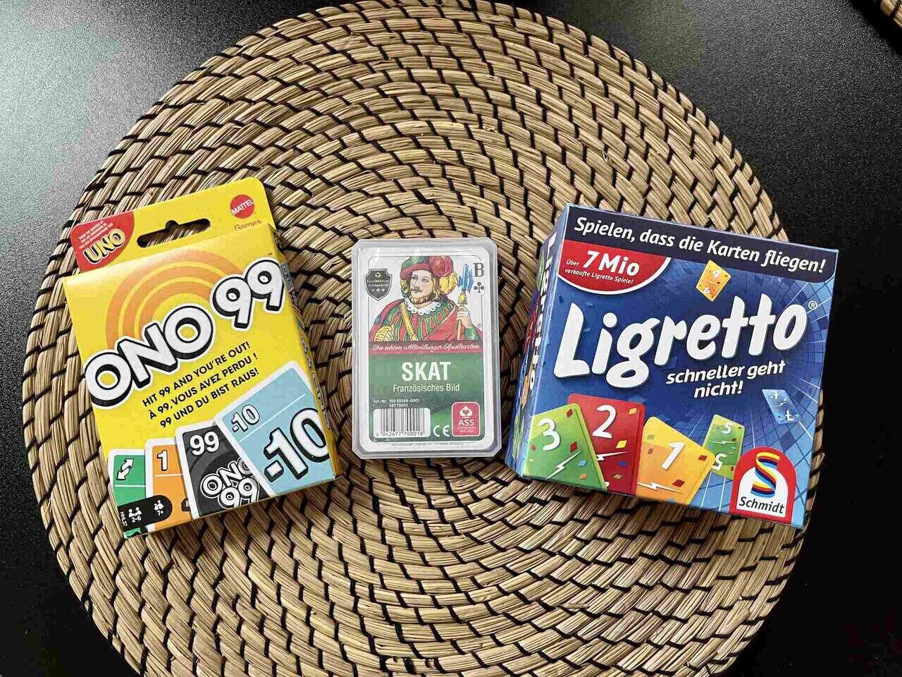Three board games: UNO, SKAT, and LIGRETTO, placed on a woven mat.