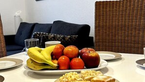 A dining area with a table set for two, featuring plates of food, a cup of coffee, and a basket of fruit. - N&N: Apartment - Schloss & Stadtnähe (Schwerin)