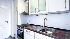 A modern kitchen with white cabinets, a stainless steel sink, and a wooden countertop. - N&N: Apartment - Schloss & Stadtnähe (Schwerin)