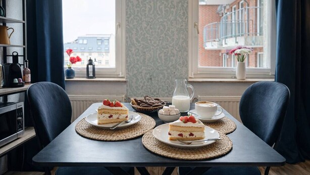 Une table à manger avec deux assiettes de gâteau, une carafe de lait et une tasse de café.