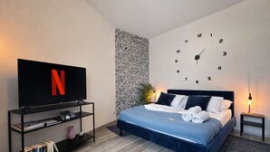 Une chambre à coucher avec un lit, une télévision, une horloge et une bibliothèque.