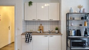 Une cuisine moderne avec des armoires blanches, un plan de travail en bois et un four à micro-ondes encastré.