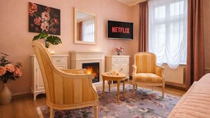 Une chambre d’hôtel confortable avec une cheminée, deux fauteuils, une table basse et un lit.
