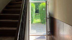 Un escalier menant à un espace extérieur abrité, d’où l’on peut admirer la verdure.