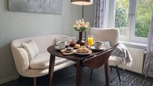Ein gemütliches Frühstücksszenario mit Tisch, Sofa und Blick ins Grüne.