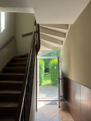 Un escalier menant à une porte vitrée qui donne sur un jardin.