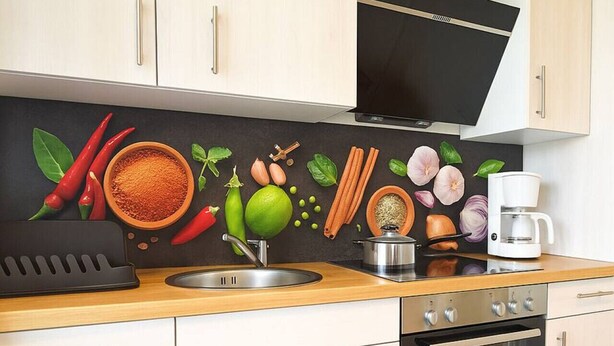 Een moderne keuken met een houten aanrecht, roestvrijstalen apparatuur en een spatwand met een ontwerp van fruit en specerijen.