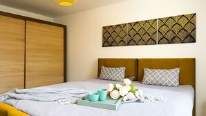 Een moderne slaapkamer met een bed, een geel hanglamp en een decoratief wandpaneel.