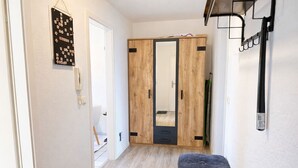 Ein Flur mit einem Holzschrank, einer Bank und einem an der Wand befestigten Regal.