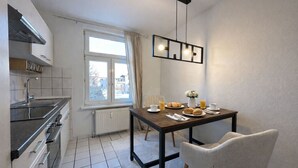 Eine moderne Küche mit Essbereich, ausgestattet mit einem für das Frühstück gedecktem Tisch, einem Heizkörper und einem Fenster mit Vorhängen.