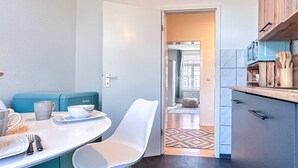 Een compacte keuken met een eethoek, uitgevoerd in modern design met een blauw-witte kleurenschema, voorzien van een magnetron en houten kastjes.