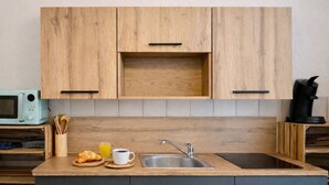 Een moderne keuken met houten kastjes, een roestvrijstalen spoelbak, een magnetron en een koffiezetapparaat.