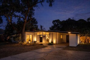 Una casa moderna amb un vestíbul ben il·luminat, grans finestres i un garatge visible.