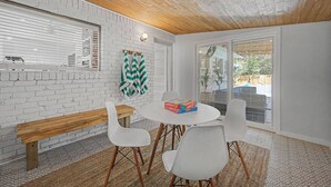 A modern interior with a white brick wall, wooden ceiling, and a round table with chairs. - Pool + Hot Tub Retreat · Sleeps 18 · Near Destin (Fort Walton Beach)