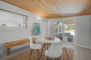 Un interior modern amb una paret de maó blanc, sostre de fusta i una taula rodona amb cadires.