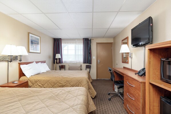 A hotel room with two beds, a desk, a television, and a bathroom. - Key Inn (Elko)