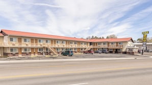 Motel amb teulada vermella, diverses habitacions i un aparcament.