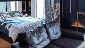 Quarto com cama, sofá e lareira.