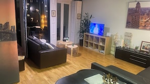 Uma sala de estar moderna com sofá de couro, mesa de centro, televisão e estante.