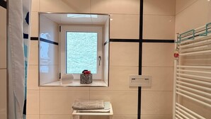 A small bathroom with a bathtub, toilet, and a window above the sink. - Large family vacation apartment near Europapark - feel like at home (Meißenheim)
