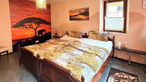 A bedroom with a large bed, a wall mural, a window, and a bedside table. - Large family vacation apartment near Europapark - feel like at home (Meißenheim)