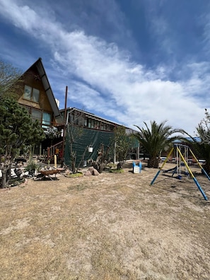 A house with a sloped roof, a fenced yard, and a swing set.