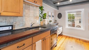A kitchen with wooden cabinets, a stone backsplash, a sink, and a window with a view.