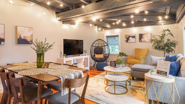 A modern living room with a dining area, a television, and a sofa.