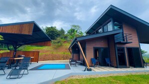 A modern house with a swimming pool, outdoor seating, and a covered patio area.